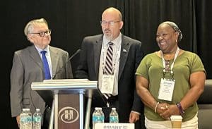 As National Legislative Director Greg Hynes looks on (left), TD President Jeremy Ferguson stands next to Local 1785 Legislative Representative Christine Ivey and declares the motion carried to create the Bus and Transit Assault Prevention and Safety Committee.