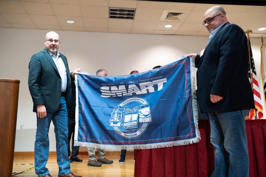 SMART Transportation Division President Jeremy R. Ferguson and General Chairperson Thomas Gholson hold a union flag at the C3RS signing ceremony in Atlanta on Thursday, Feb. 15.